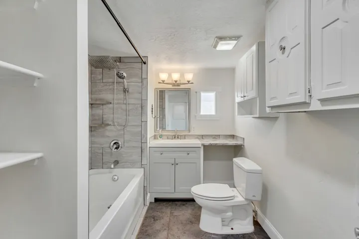 Bathroom with vanity, bathtub / shower combination, and a textured ceiling