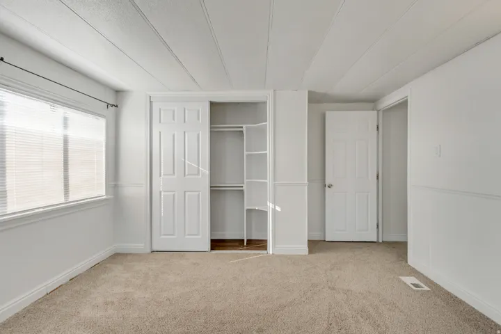 Unfurnished bedroom featuring light carpet and a closet