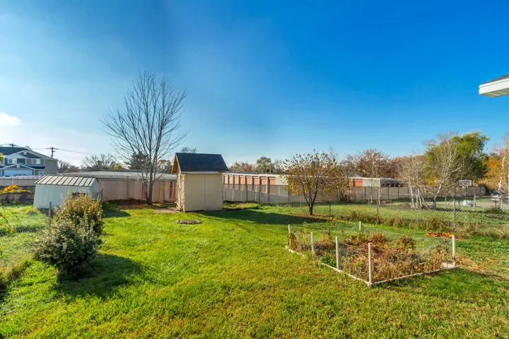 Fenced backyard featuring a storage unit and a vegetable garden