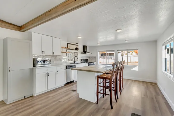 Kitchen with white cabinetry, wood counters, a breakfast bar area, a center island, and healthy amount of natural light