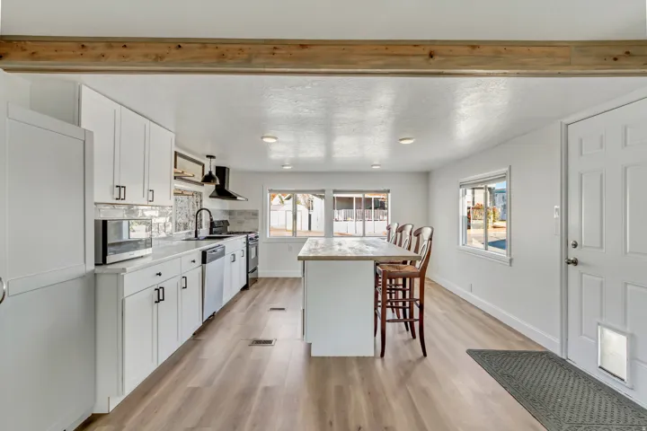 Kitchen featuring white cabinetry, light countertops, a kitchen bar, stainless steel appliances, and recessed lighting