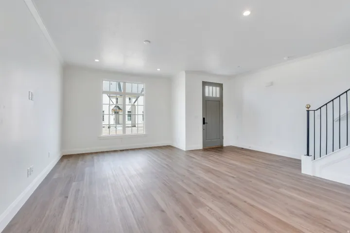 Unfurnished living room featuring light wood-style flooring, crown molding, stairway, and recessed lighting