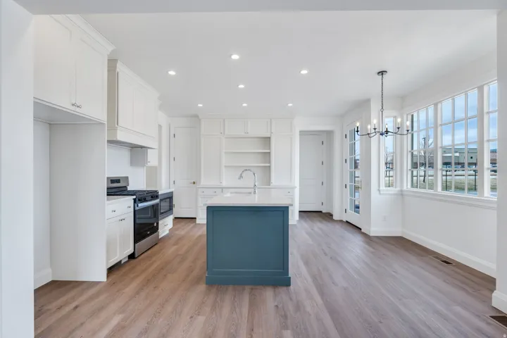 Kitchen featuring white cabinets, a kitchen island with sink, stainless steel gas range oven, pendant lighting, and recessed lighting