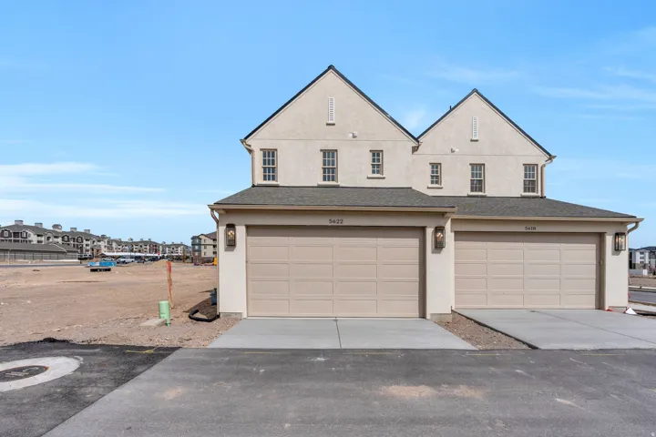 View of front facade with concrete driveway, stucco siding, a garage, and roof with shingles
