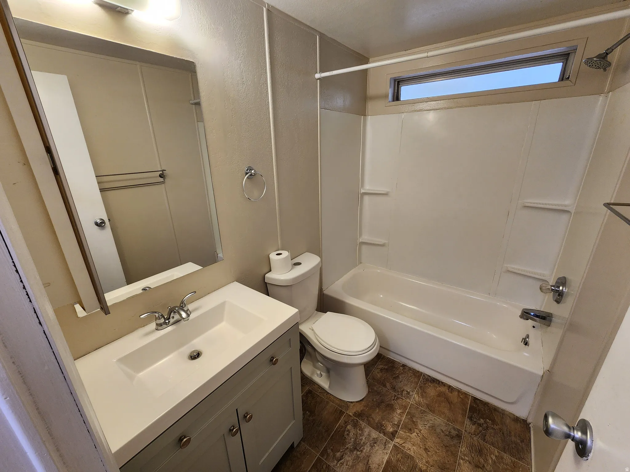 Bathroom featuring vanity, bathing tub / shower combination, and stone finish floors