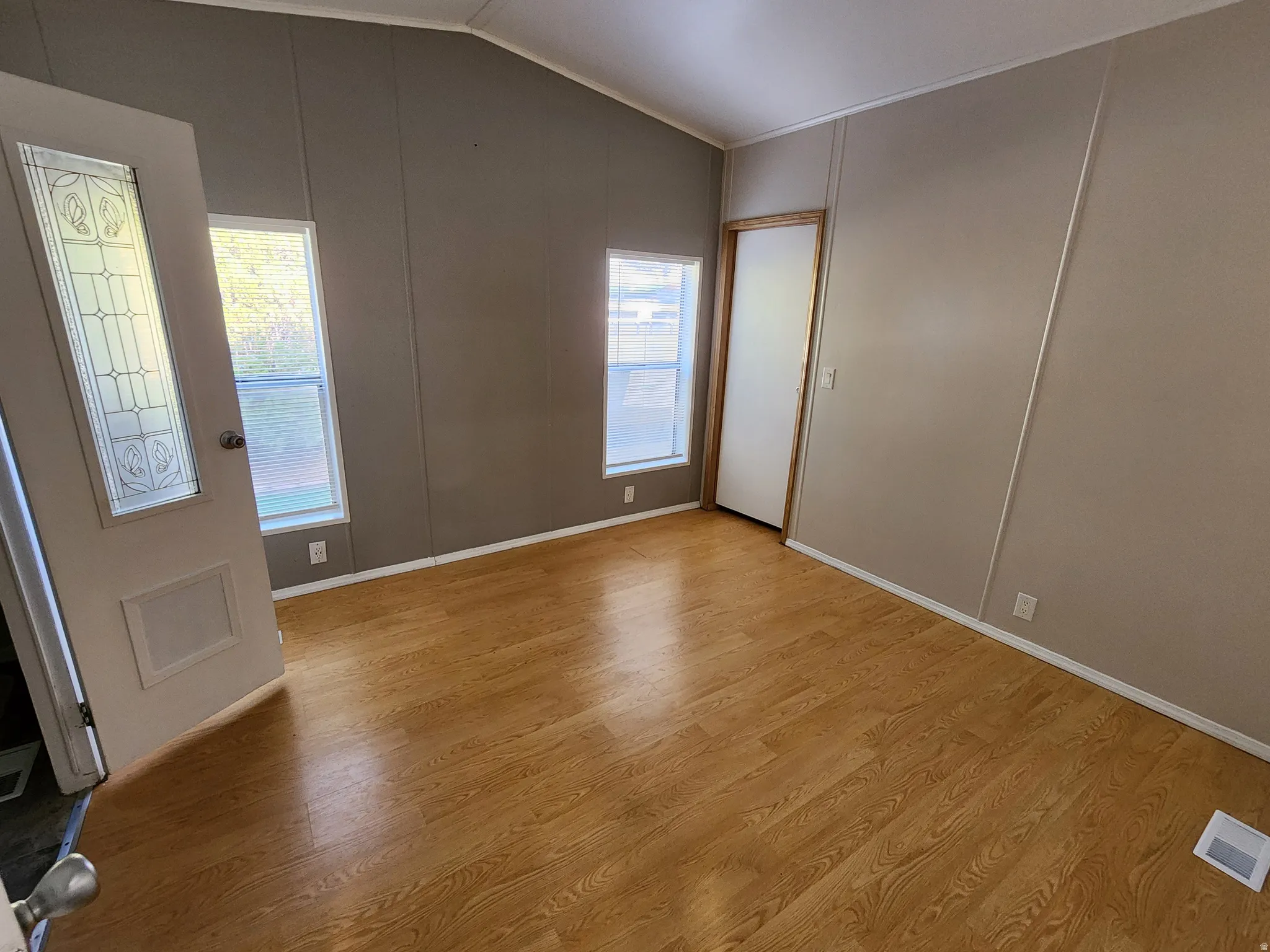 Entryway featuring a decorative wall, lofted ceiling, and light wood-type flooring