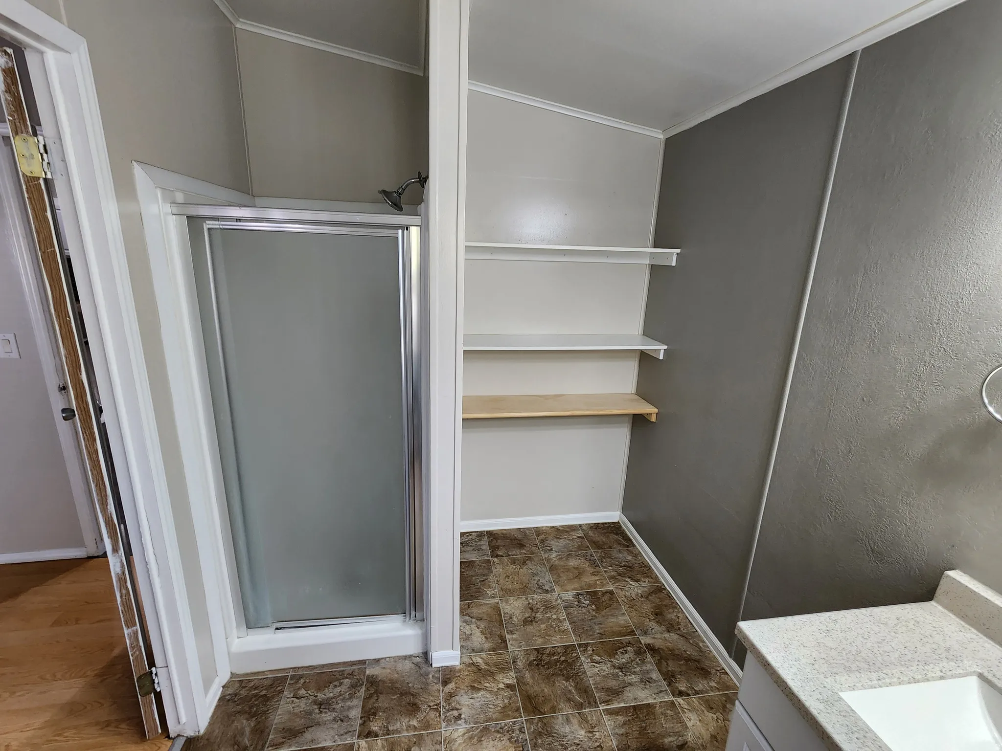 Bathroom with vanity, a stall shower, ornamental molding, and stone finish flooring