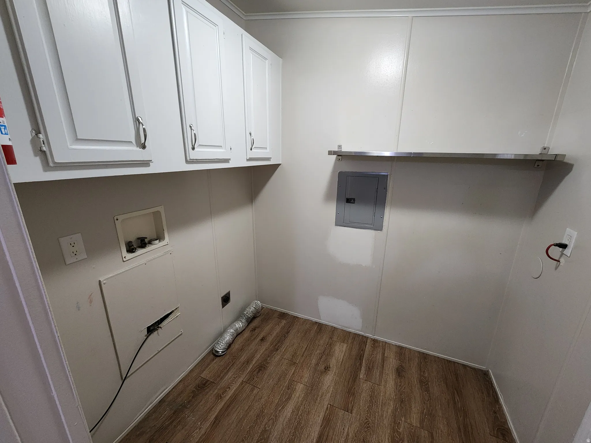 Washroom featuring dark wood-style flooring, electric panel, cabinet space, and hookup for a washing machine