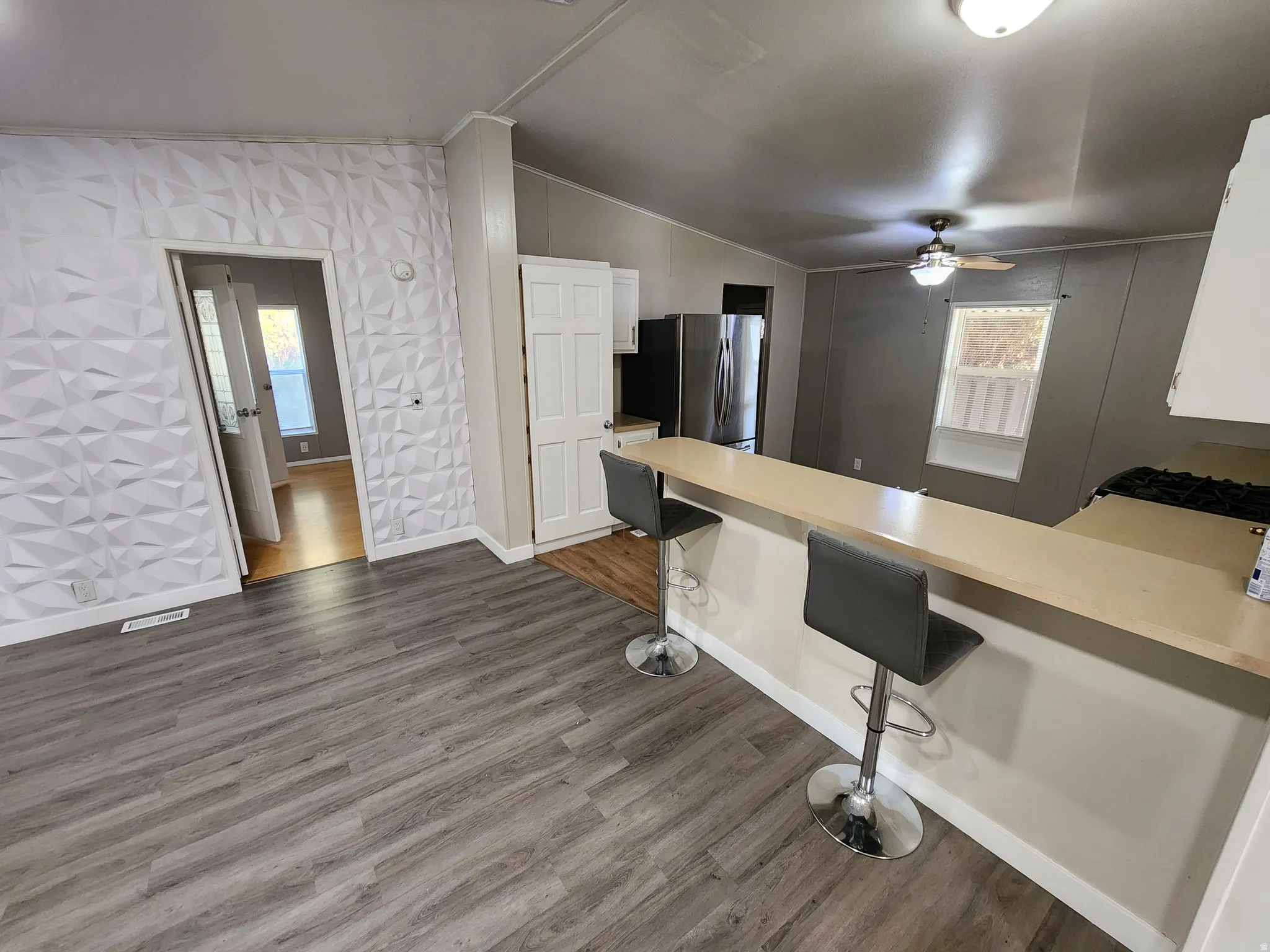Kitchen featuring a breakfast bar area, a peninsula, light countertops, white cabinets, and lofted ceiling