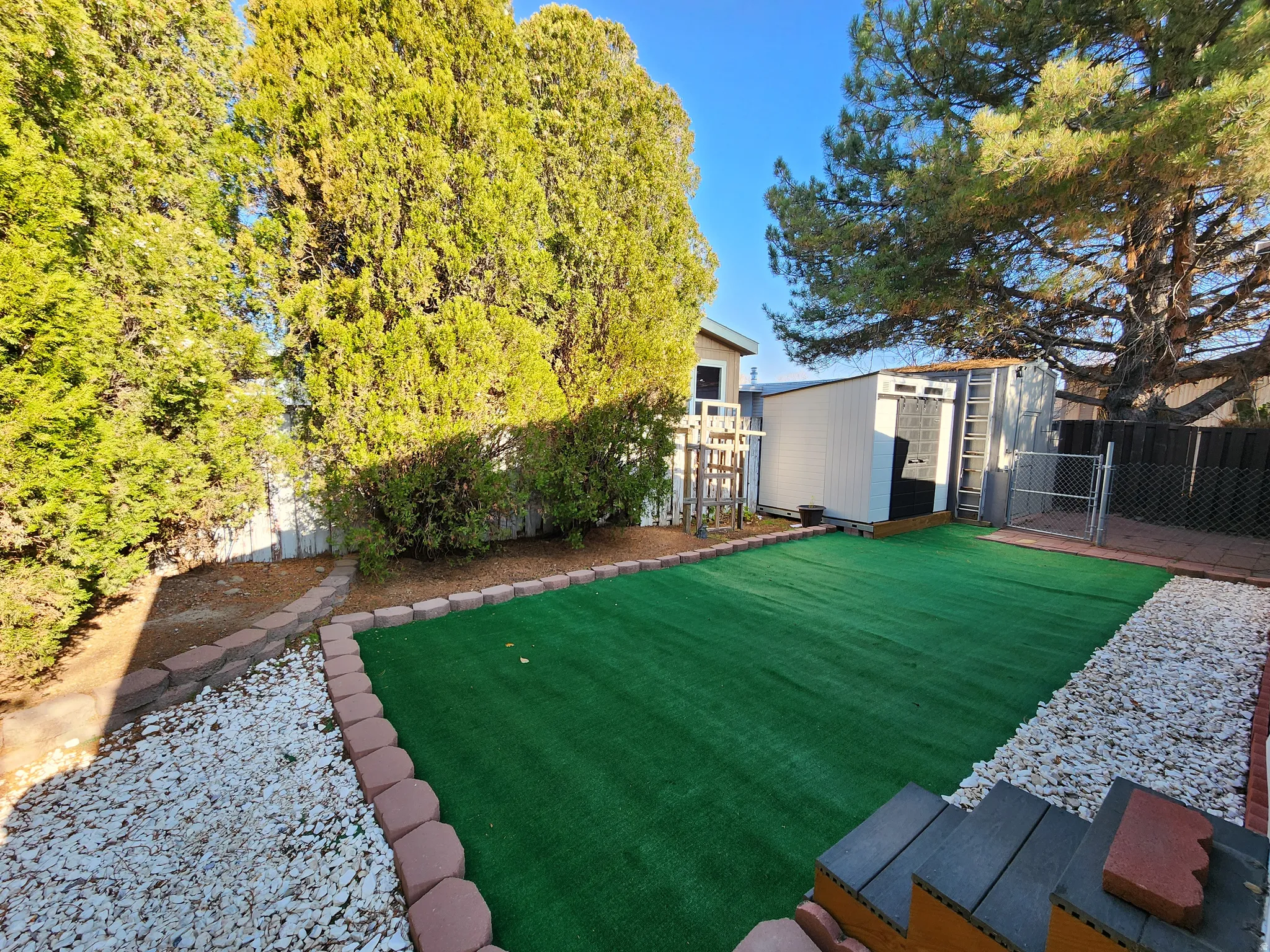 Fenced backyard featuring a shed and a gate
