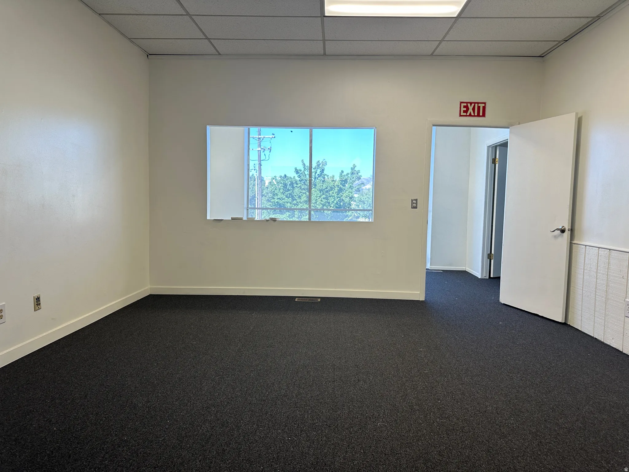 Empty room with dark carpet and a drop ceiling