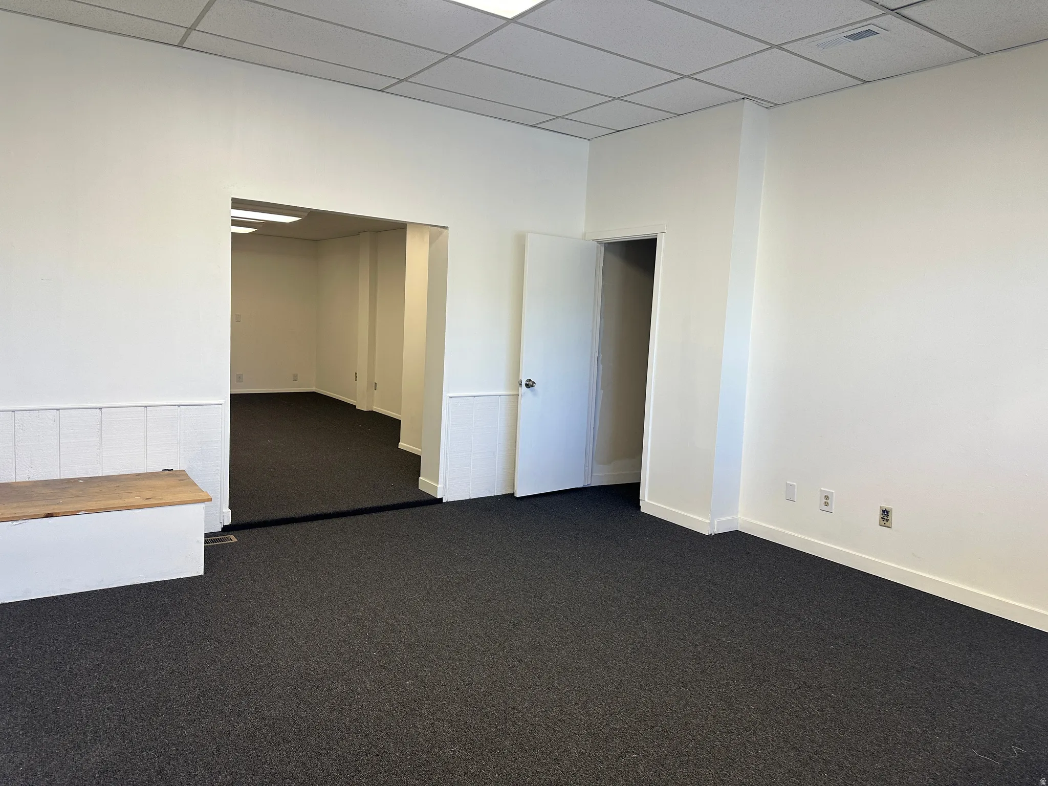 Empty room featuring dark colored carpet and a drop ceiling