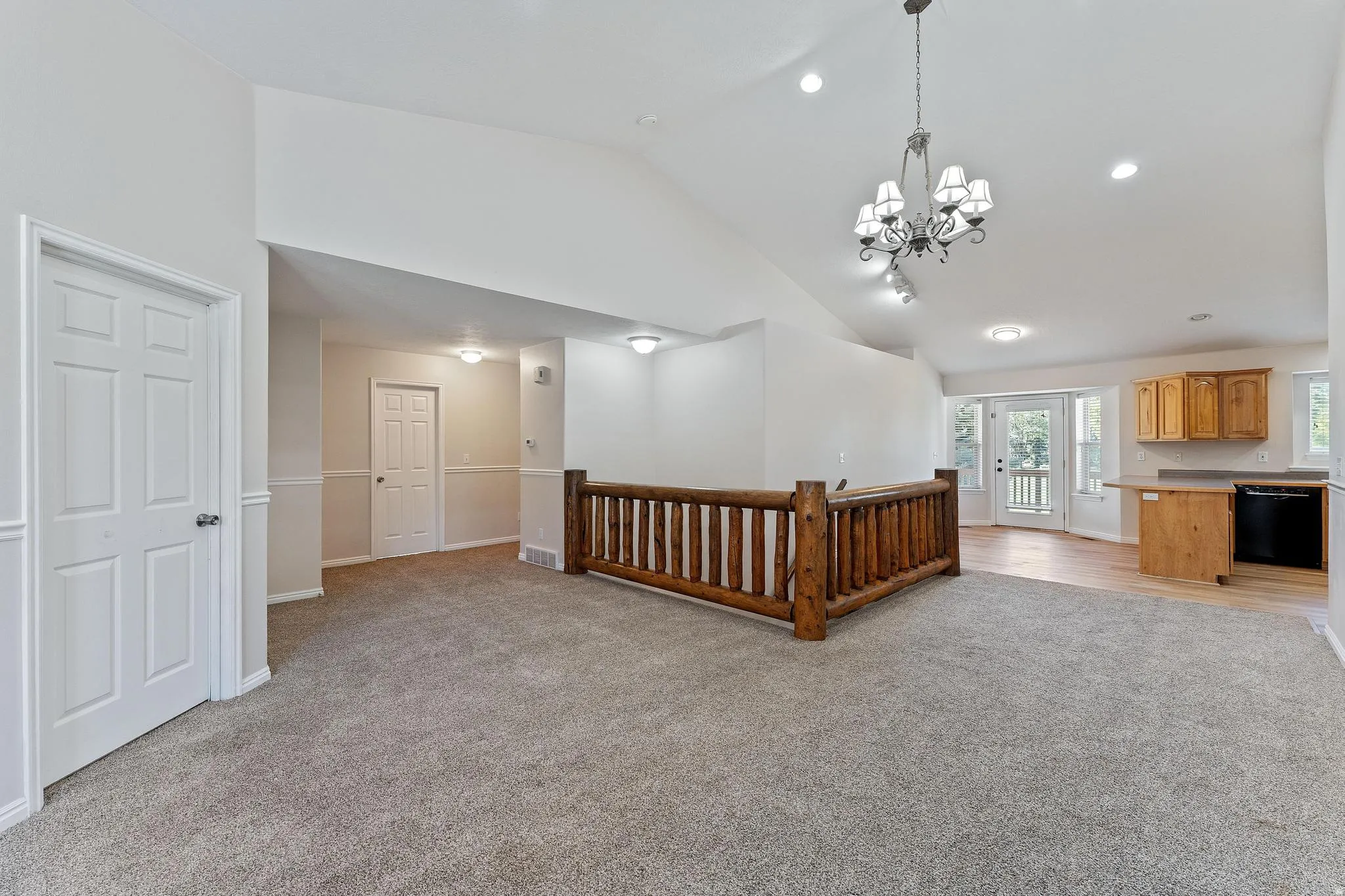 Living area with light colored carpet, high vaulted ceiling, recessed lighting, and a chandelier