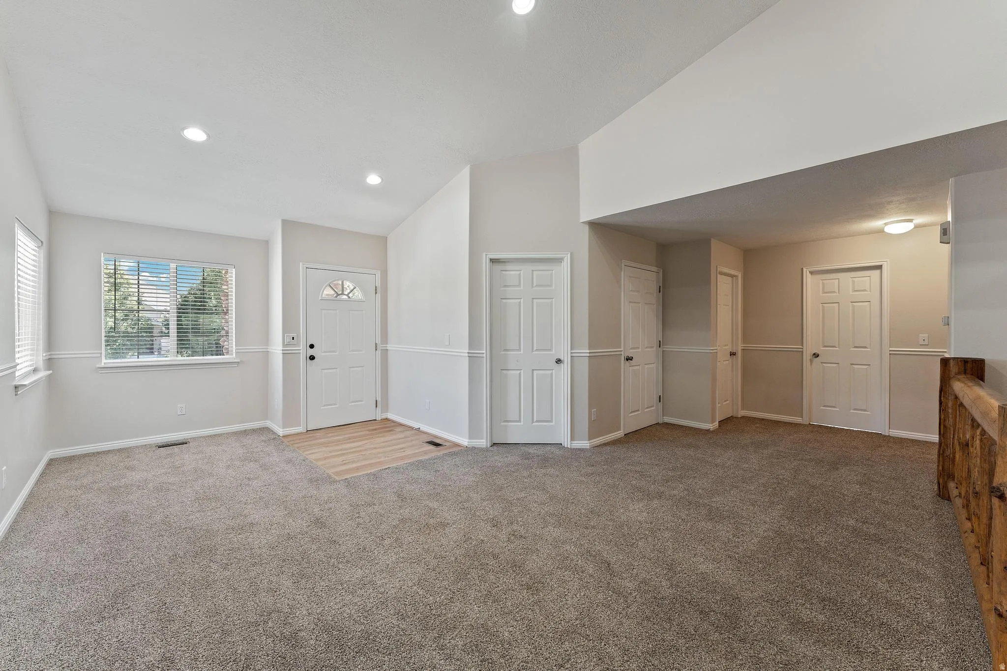 Carpeted entrance foyer featuring vaulted ceiling and recessed lighting