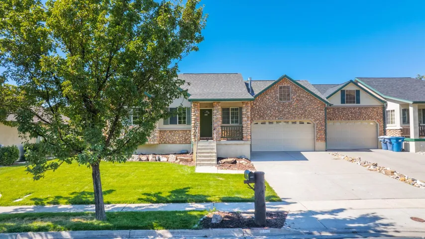 View of front of home with a porch, concrete driveway, a front yard, stone siding, and a shingled roof