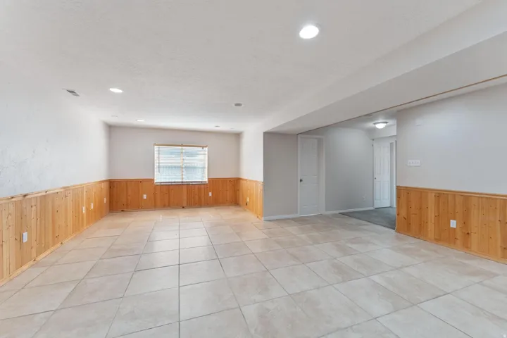 Unfurnished room featuring wooden walls, wainscoting, light tile patterned floors, a textured ceiling, and recessed lighting