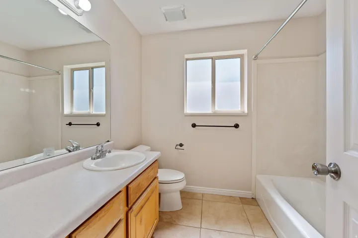 Bathroom featuring vanity, shower / tub combination, light tile patterned floors, and healthy amount of natural light