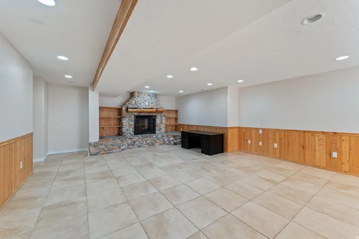 Unfurnished living room with a wainscoted wall, wooden walls, a fireplace, light tile patterned floors, and a textured ceiling