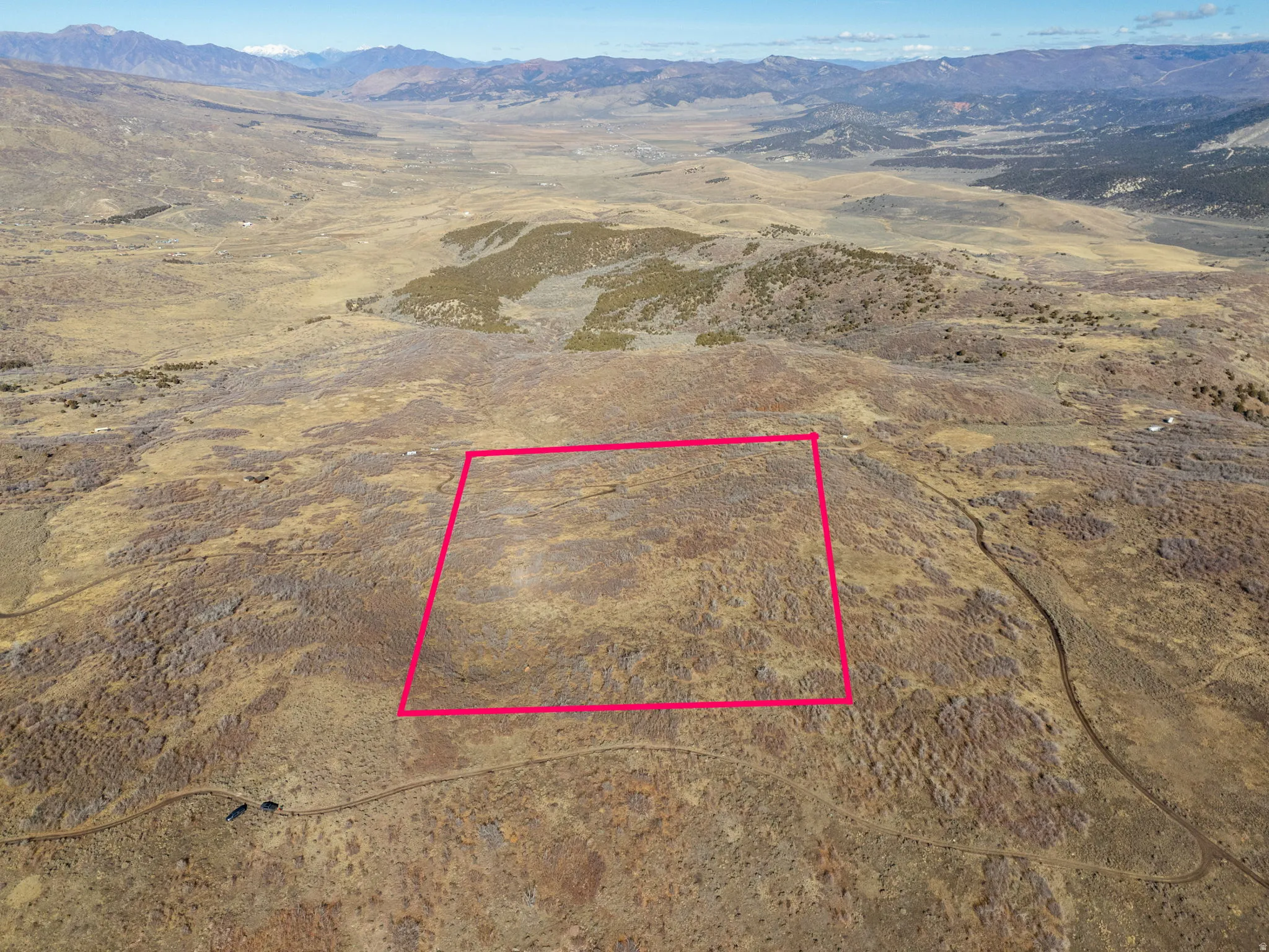 Aerial overview of property's location featuring a mountainous background, property parcel outlined, and rural landscape