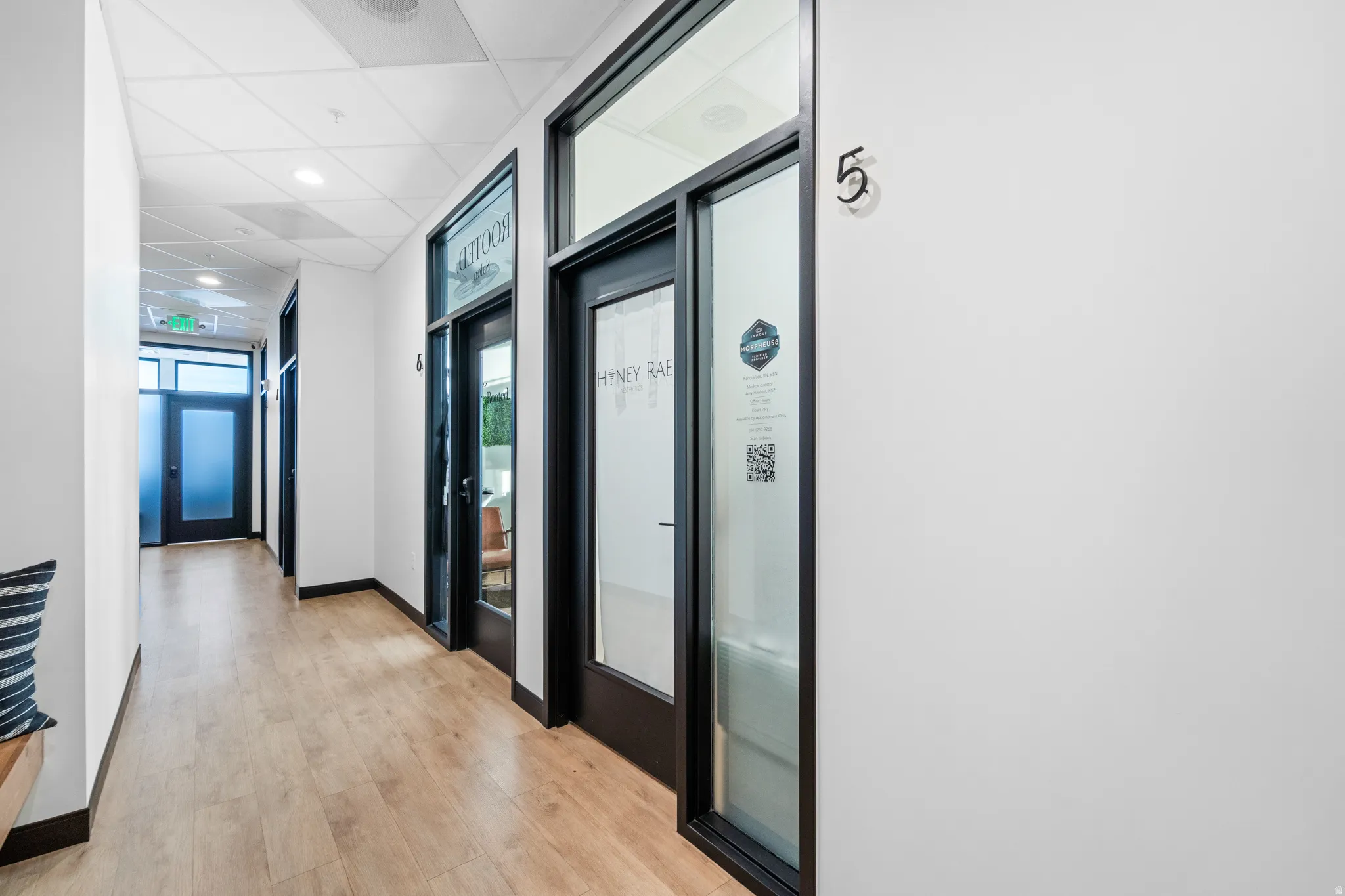 Hall featuring a drop ceiling and light wood-style flooring
