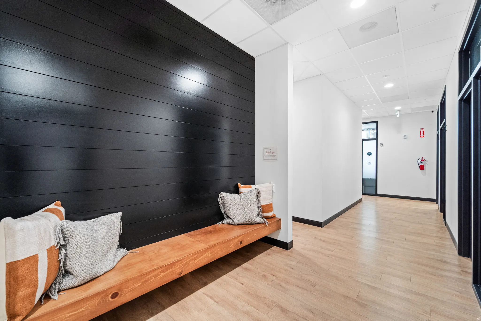 Hallway featuring a drop ceiling, light wood-style flooring, recessed lighting, and an accent wall