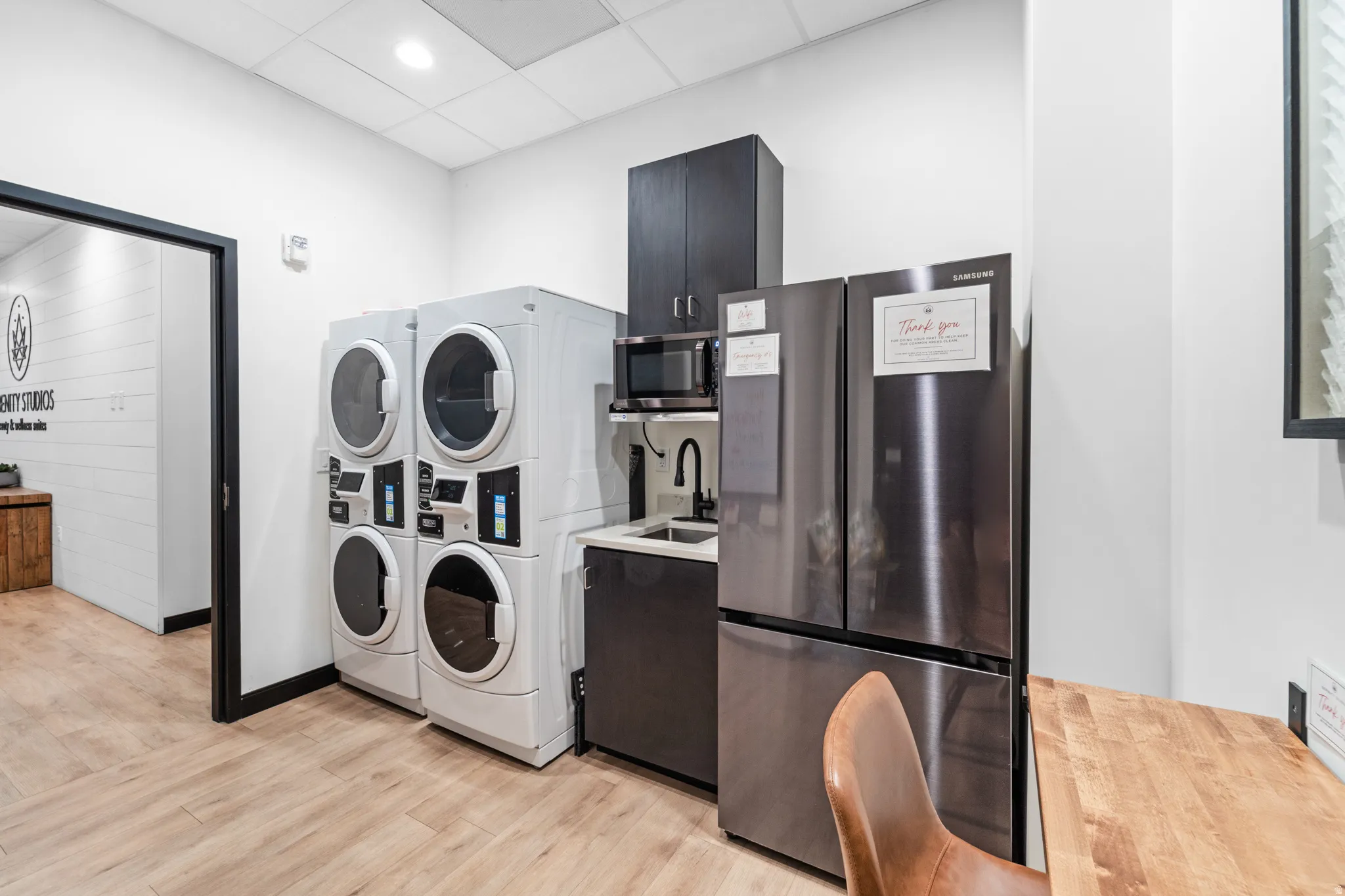 Washroom featuring a drop ceiling, stacked washer / drying machine, and recessed lighting