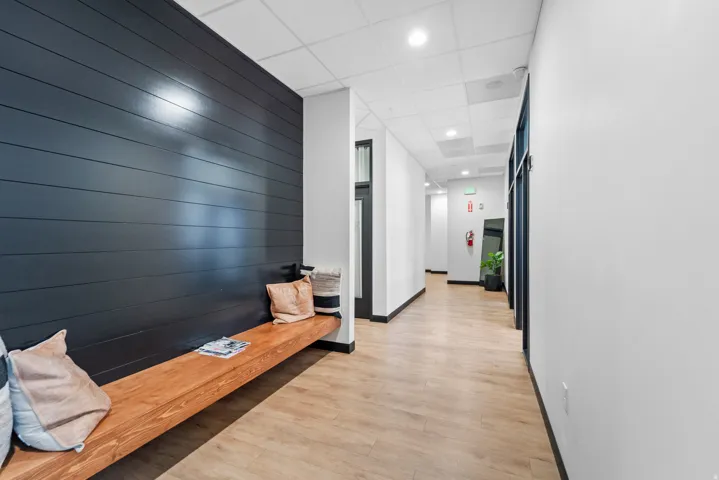 Hall featuring an accent wall, light wood-style floors, wooden walls, a drop ceiling, and recessed lighting