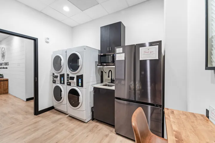 Washroom featuring a drop ceiling, stacked washer / drying machine, and recessed lighting