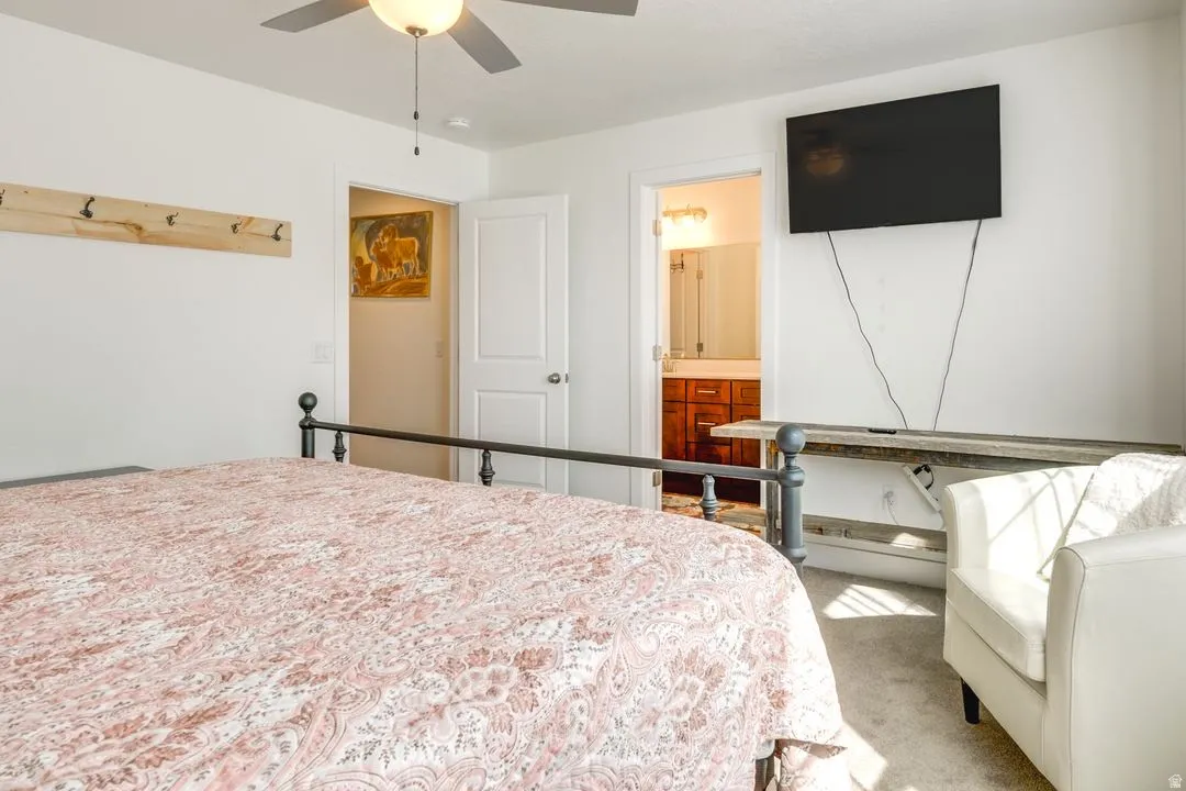 Bedroom featuring carpet flooring, ceiling fan, and ensuite bathroom