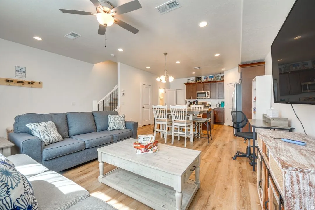 Living area with stairway, light wood-style floors, a chandelier, recessed lighting, and ceiling fan