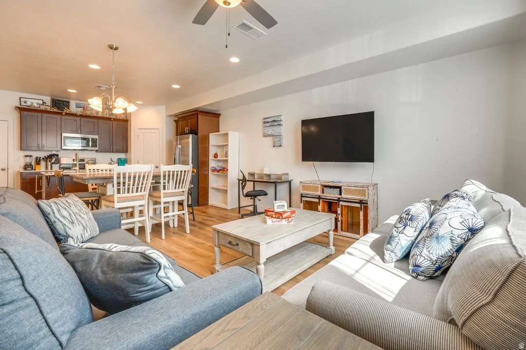 Living room featuring light wood-style flooring, recessed lighting, a chandelier, and ceiling fan
