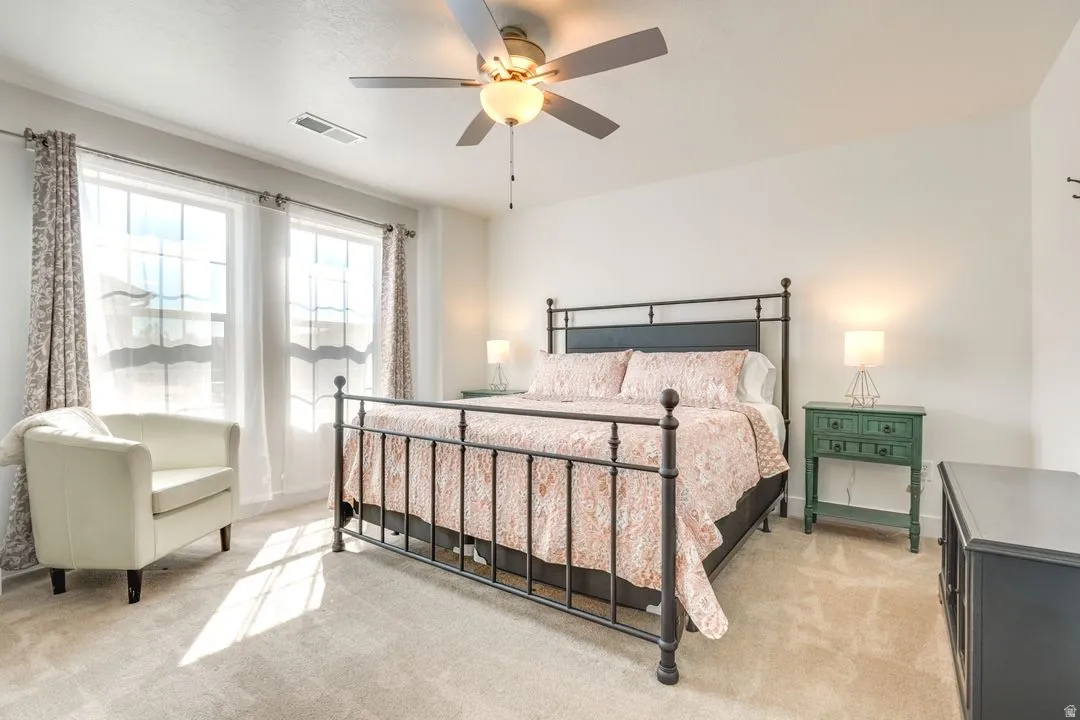 Bedroom with light colored carpet and a ceiling fan