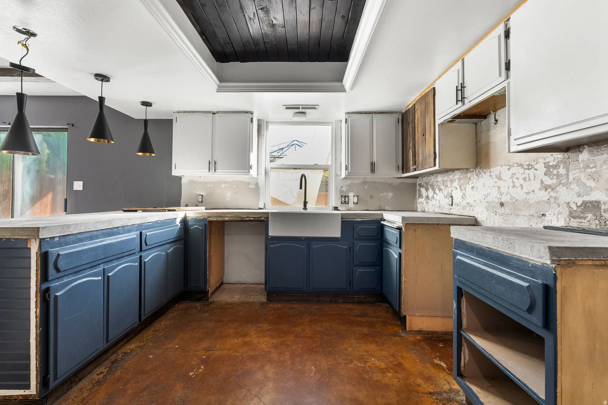 Kitchen featuring a tray ceiling, blue cabinets, decorative backsplash, concrete floors, and wooden ceiling