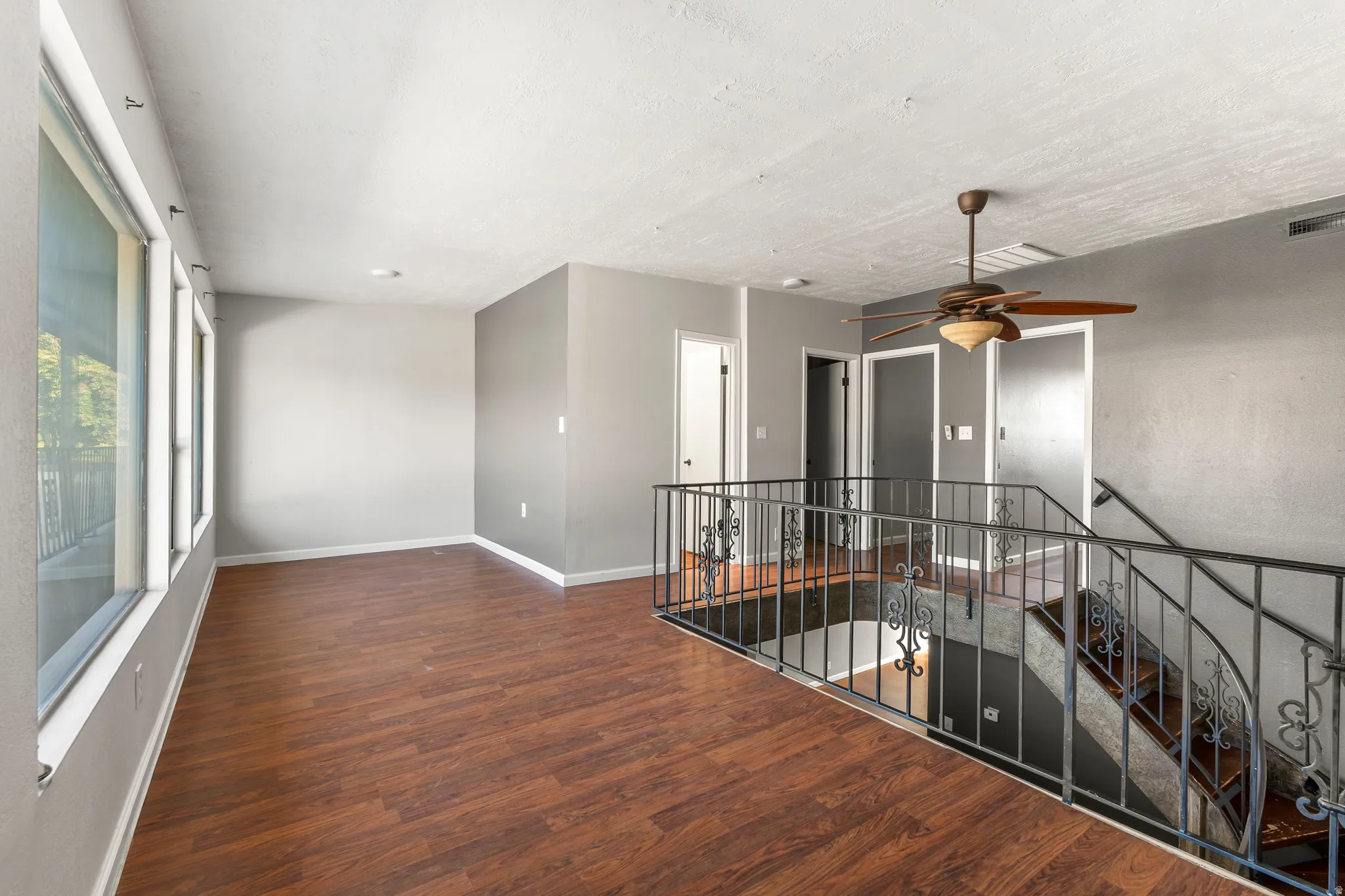 Empty room featuring ceiling fan and dark wood-style flooring