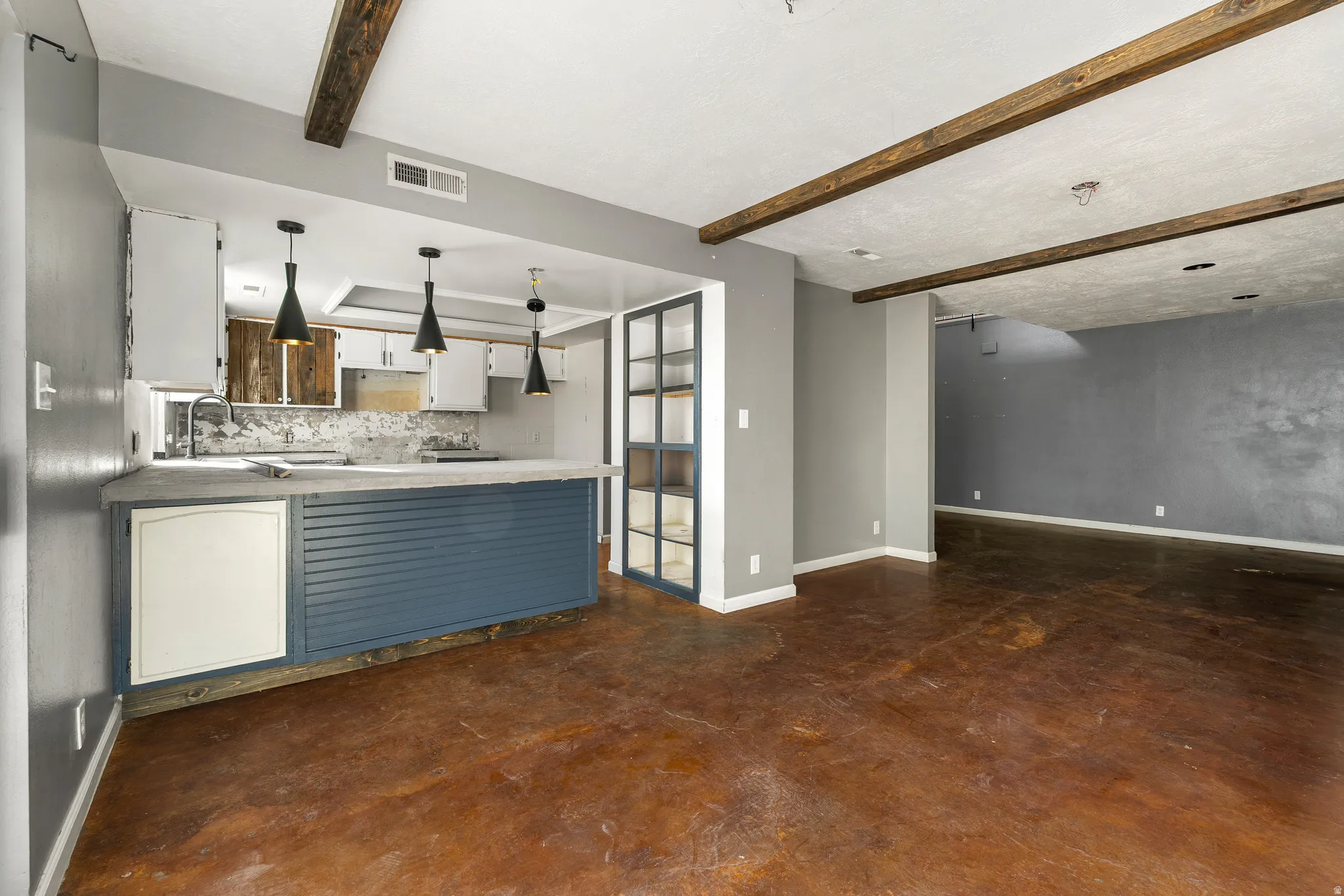 Unfurnished living room featuring finished concrete floors and beamed ceiling