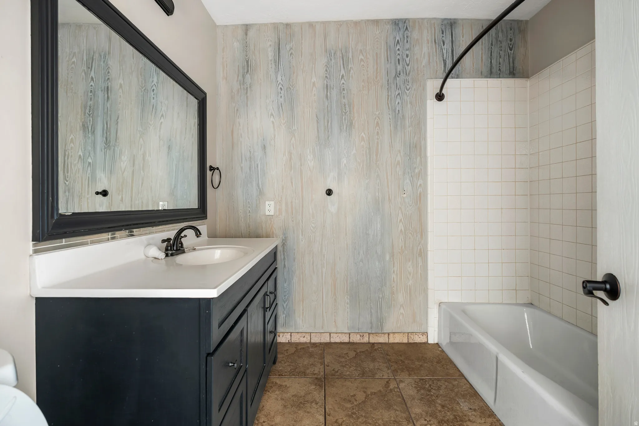 Full bath featuring tub / shower combination, vanity, and dark tile patterned floors
