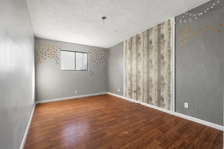 Spare room featuring a textured ceiling, wood finished floors, and a textured wall