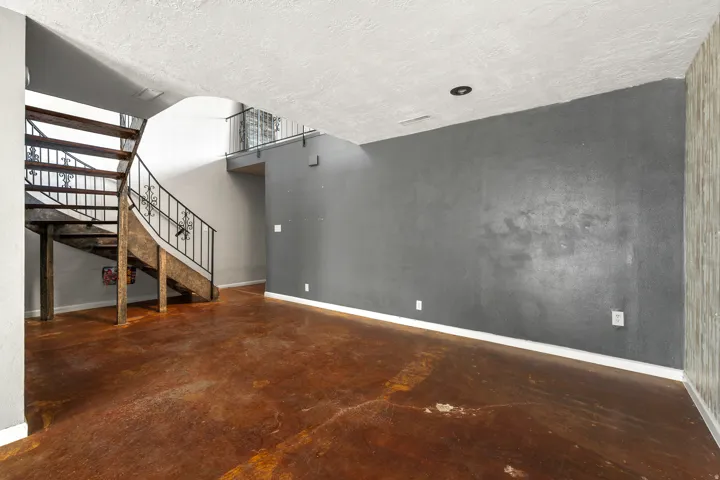 Unfurnished living room with concrete floors, stairs, and a textured ceiling