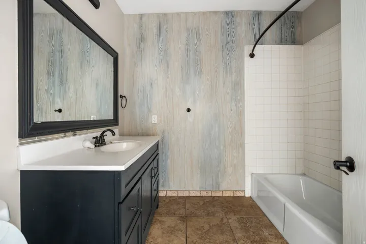 Full bath featuring tub / shower combination, vanity, and dark tile patterned floors