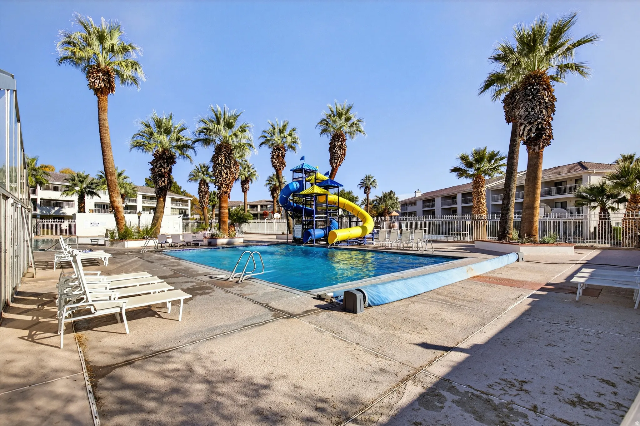 Community pool featuring a water slide and a patio