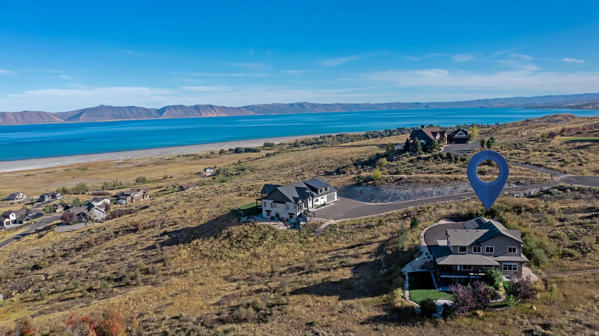 Elevated property with a large deck overlooking a body of water and distant mountains