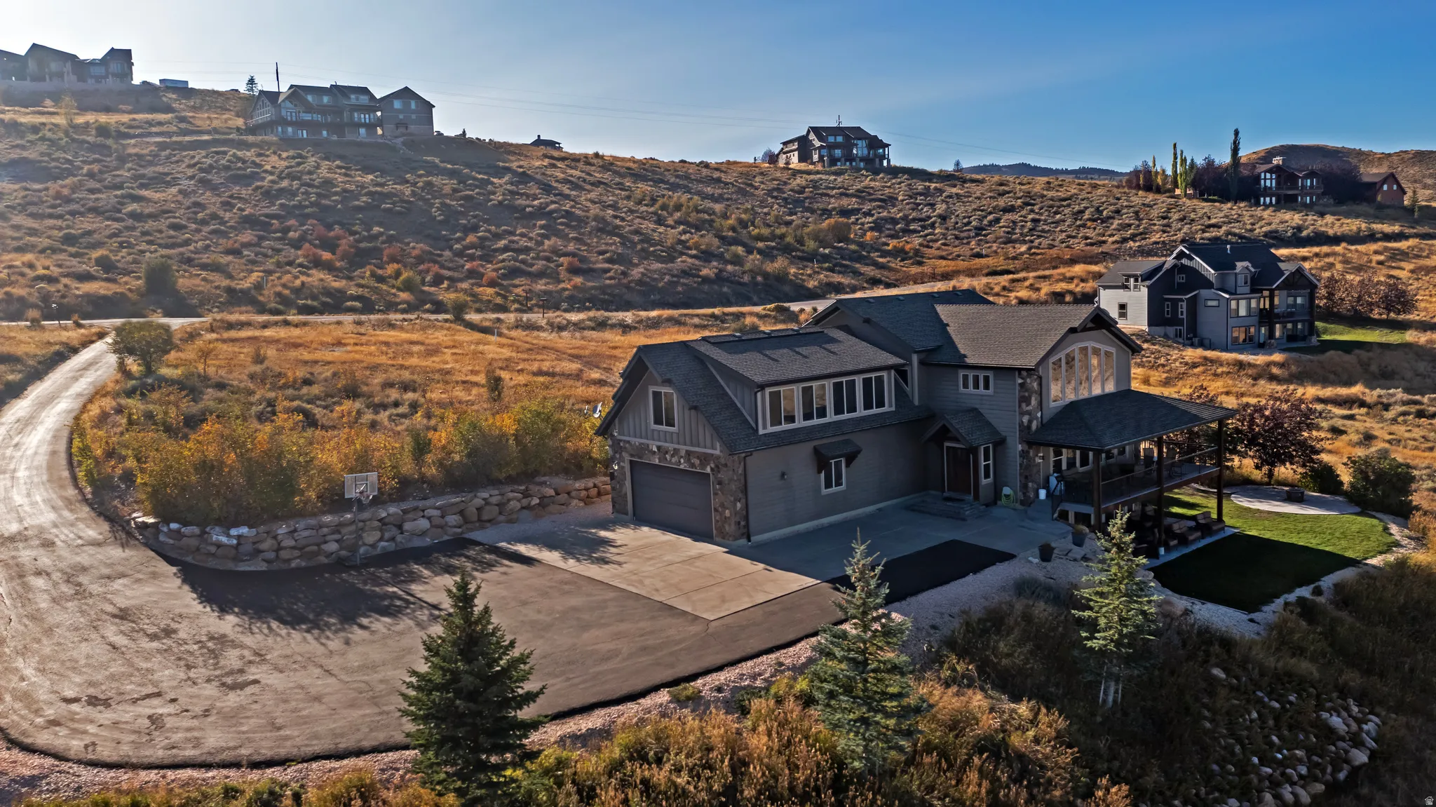 Exterior featuring a multilevel design, a covered deck, an attached two-car garage, and a sloped landscape with natural vegetation
