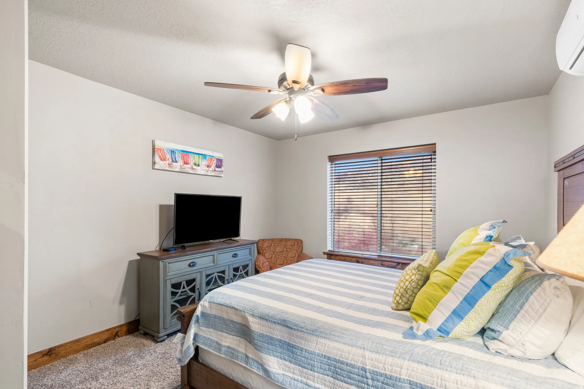 Carpeted bedroom featuring a wall mounted air conditioner and a ceiling fan