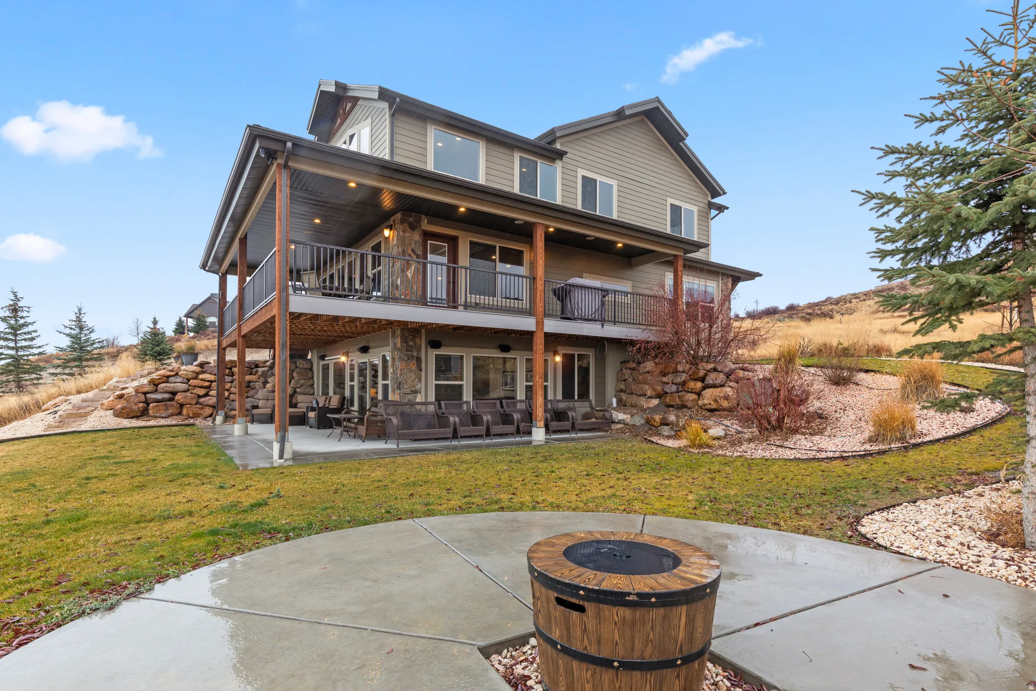 Back of property featuring a patio, stone siding, and a yard