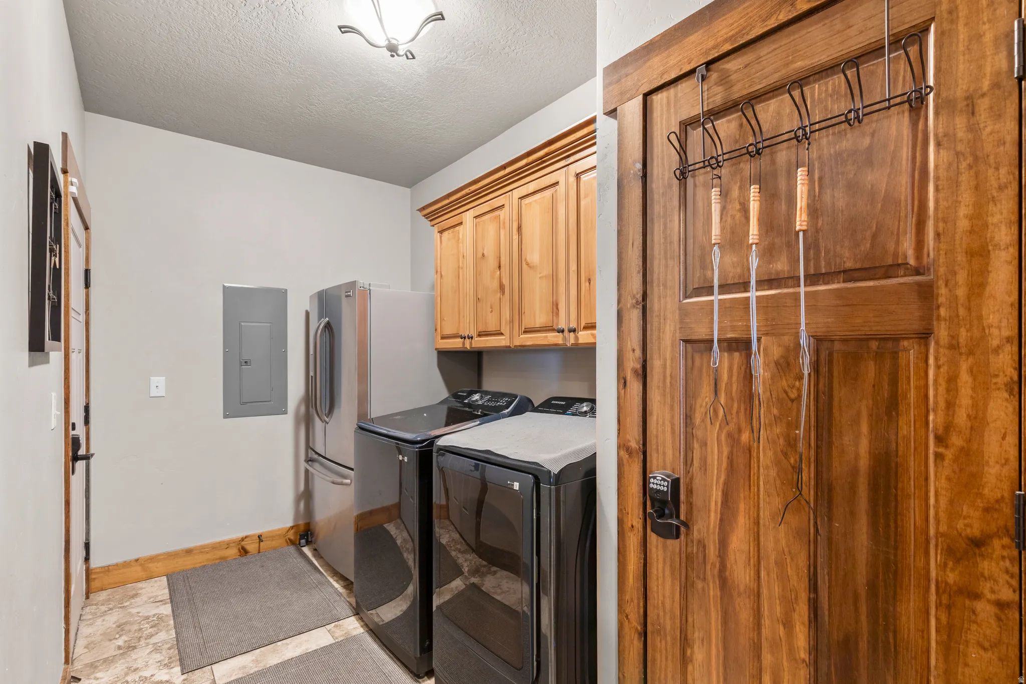 Washroom featuring cabinet space, electric panel, a textured ceiling, and washer and dryer