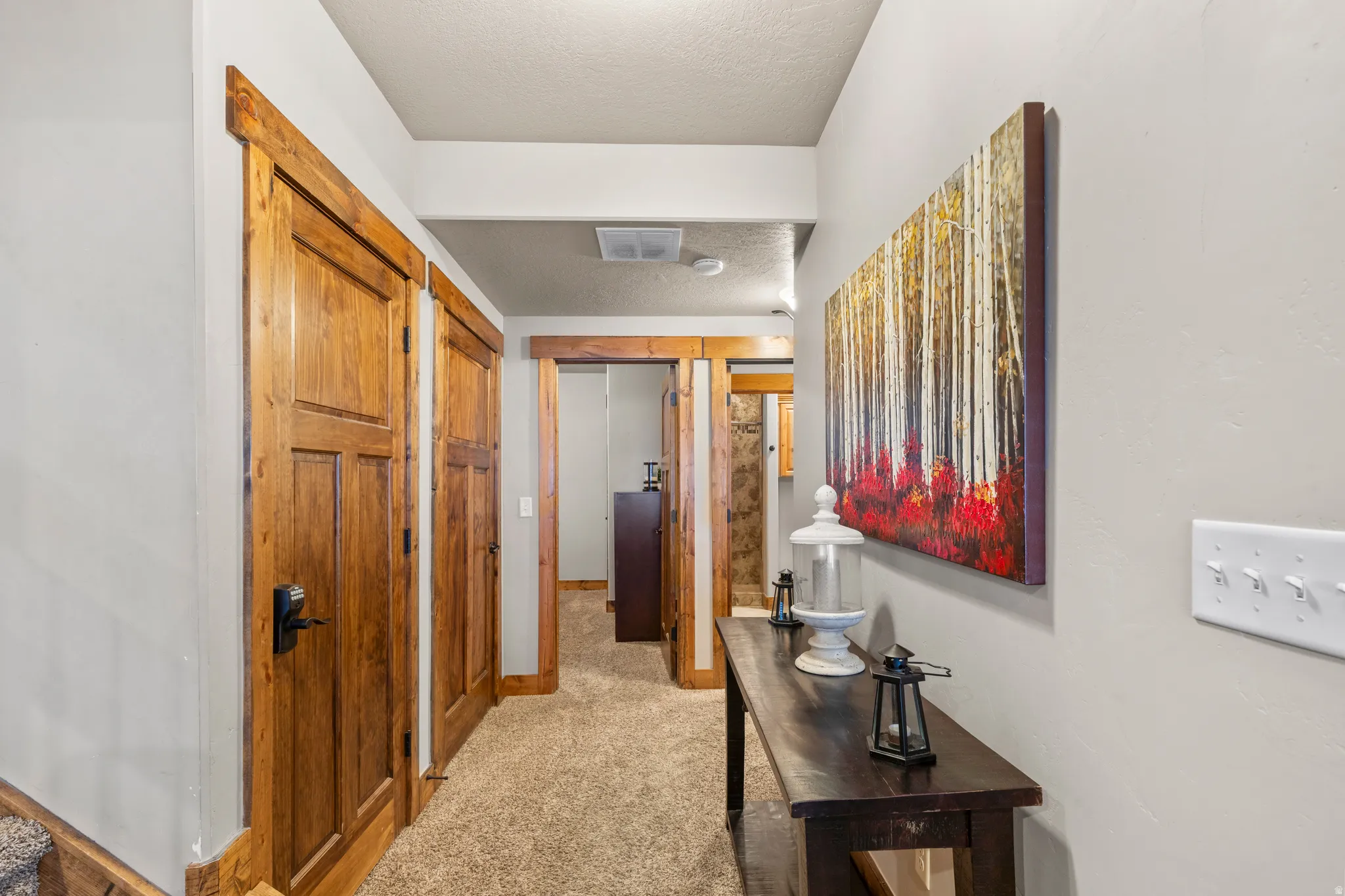 Hall with a textured ceiling and light colored carpet