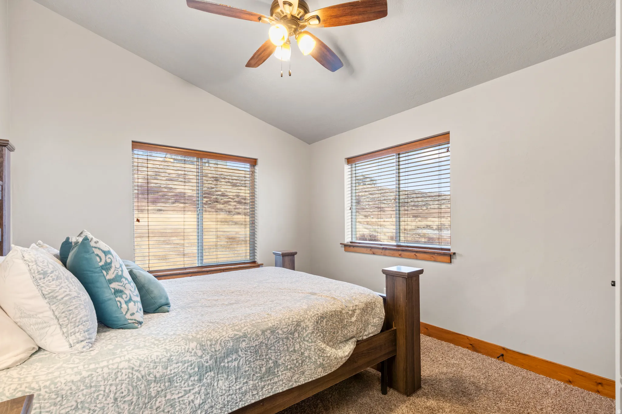Carpeted bedroom featuring vaulted ceiling and a ceiling fan