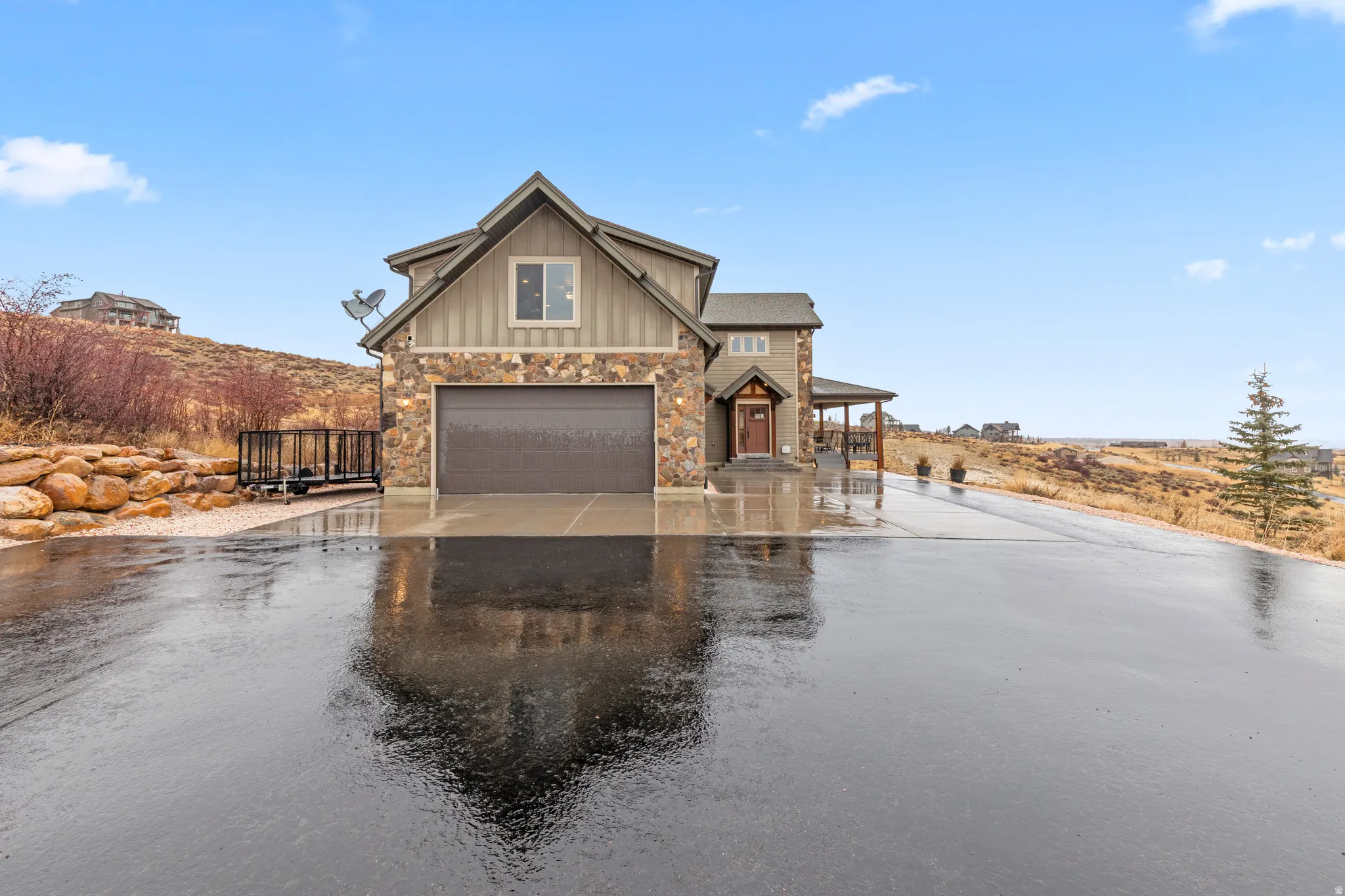 View of front of house featuring asphalt driveway, board and batten siding, stone siding, and a porch