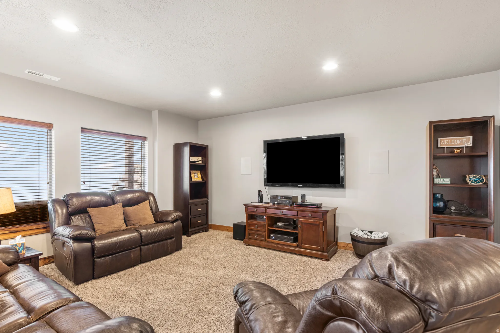 Living area with light colored carpet and recessed lighting