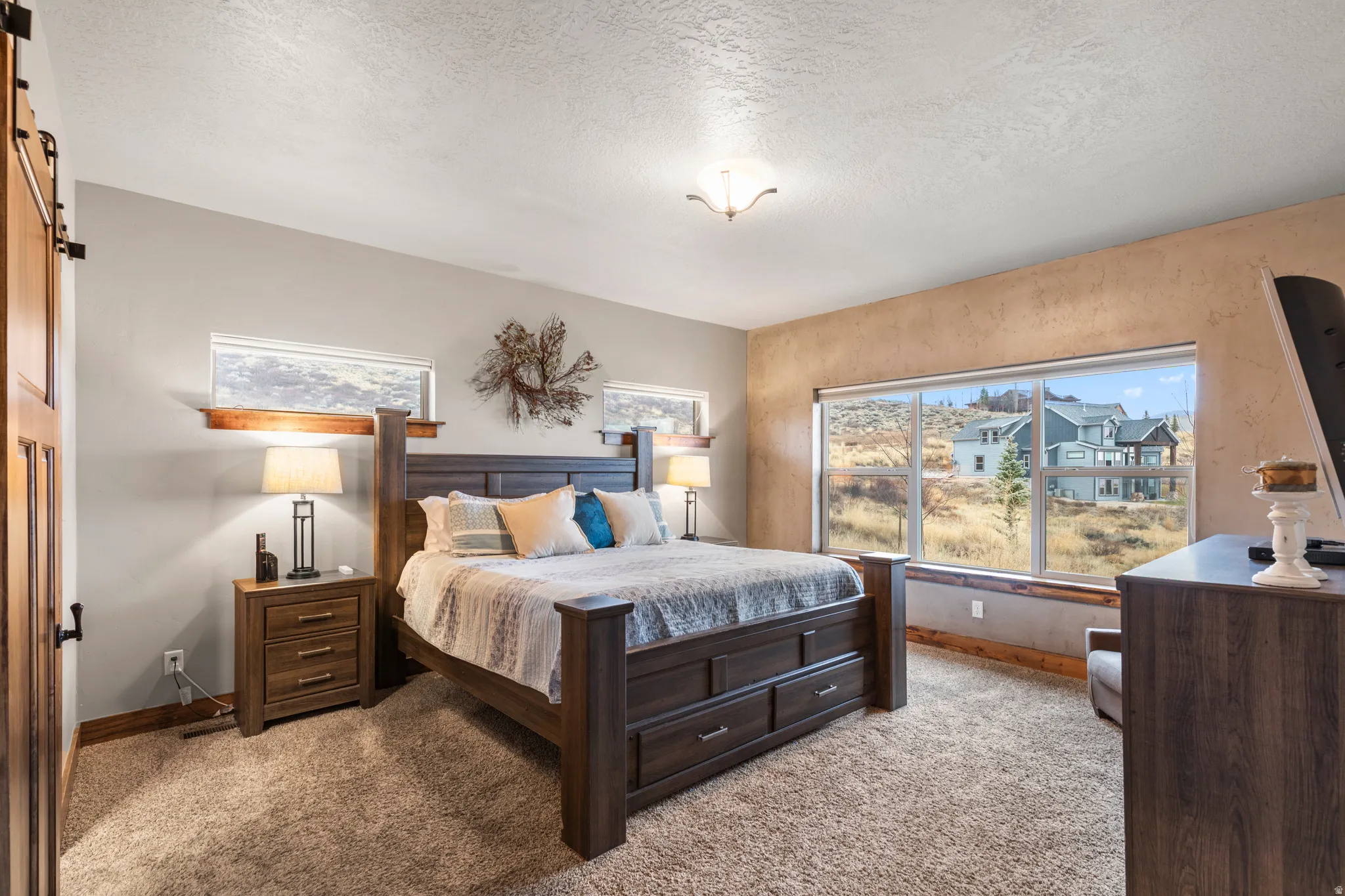 Bedroom with a barn door, carpet floors, and a textured ceiling